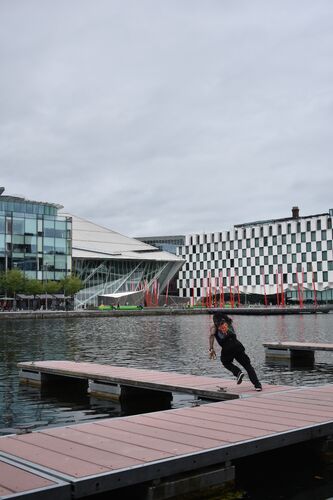 A figure running down the dock at Charlotte Quay with Grand Canal Dock in the background