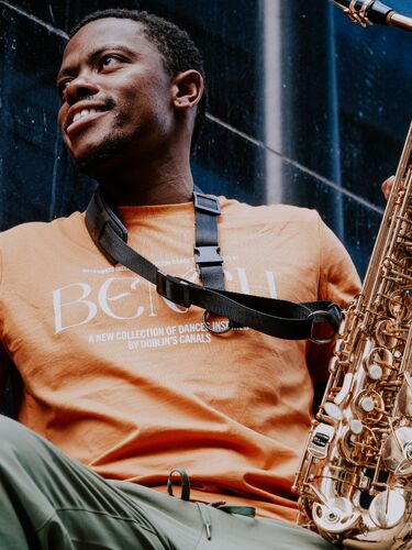 A figure seen from below wearing a BENCH tshirt and holding a saxophone